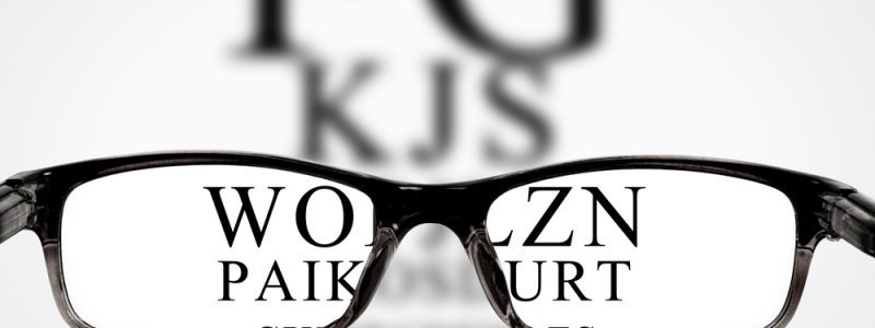 Sight test seen through eye glasses, white background isolated